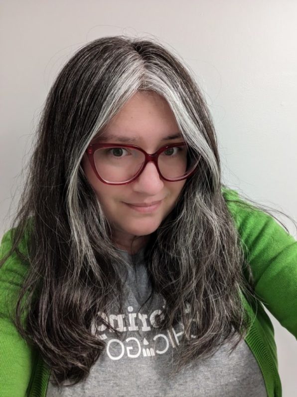 A woman with graying hair and red glasses smiles at a camera. Her shirt reads "Tutoring Chicago."